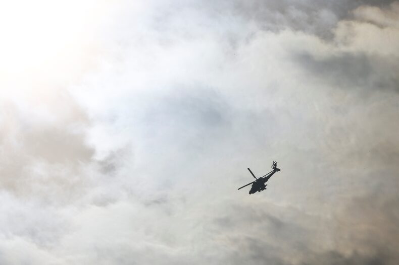 An Israeli Apache helicopter flies in the sky, amid the ongoing conflict between Israel and Hamas, as seen from southern Israel