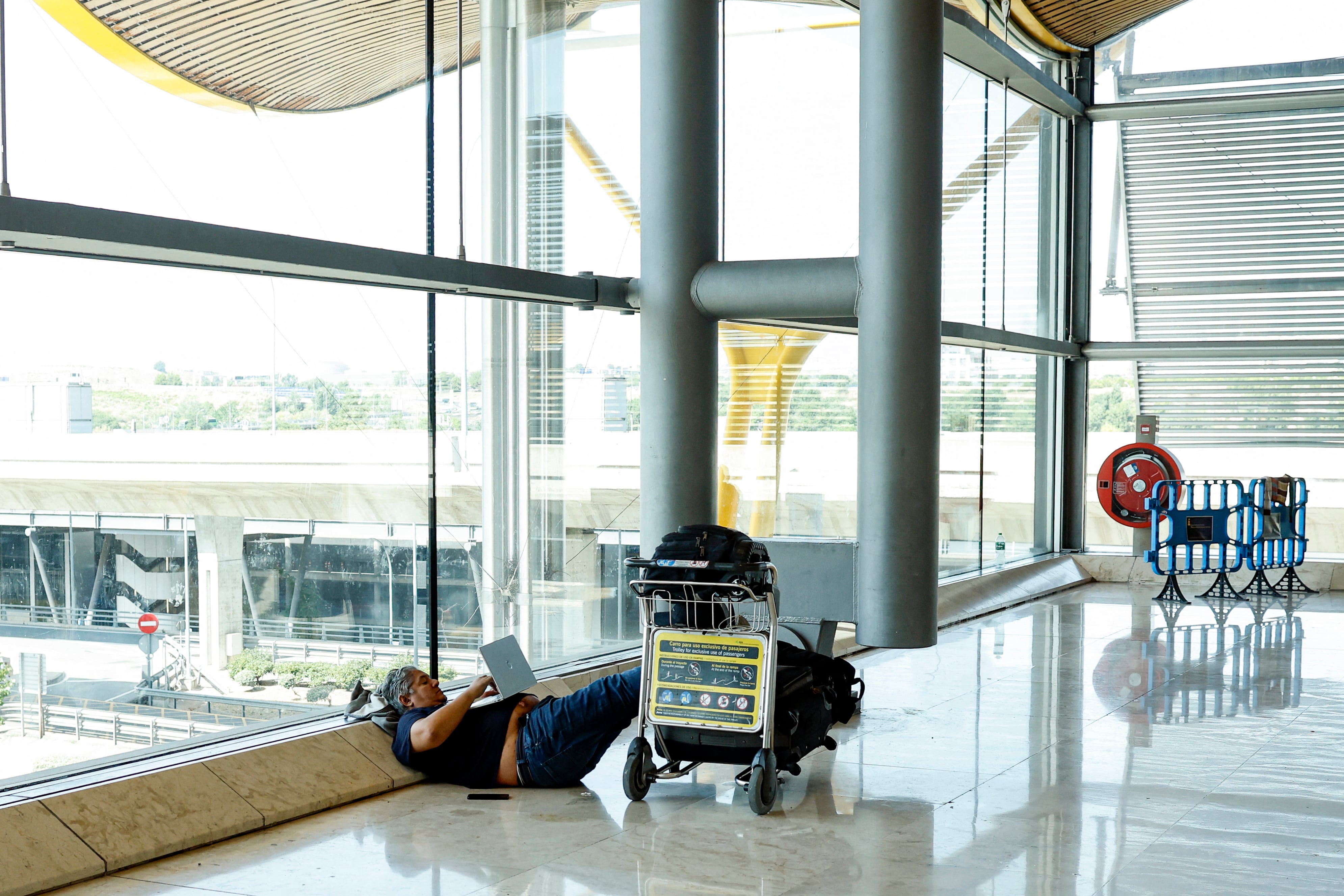 Un pasajero yace en el suelo mientras espera su facturación en la Terminal 4 del Aeropuerto Adolfo Suárez Madrid-Barajas, Madrid, el 19 de julio de 2024, en medio de una interrupción masiva del sistema informático a nivel mundial. Foto: AFP