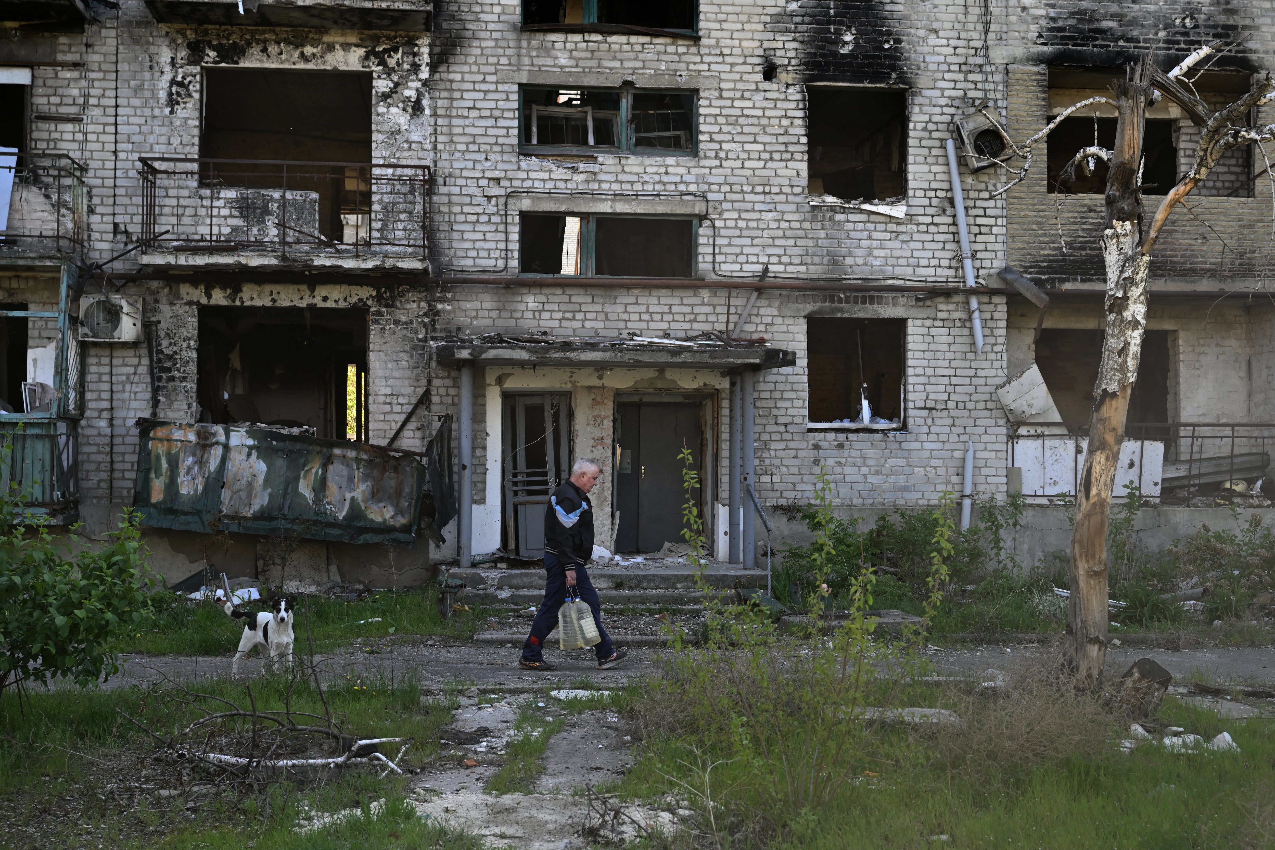Mykola, un residente local de 64 años, carga botellas de agua de un pozo frente a un edificio residencial gravemente dañado en la ciudad de Lyman, cerca de la línea del frente en la región de Donetsk, el 29 de abril de 2025, durante la invasión rusa de Ucrania. Foto: AFP