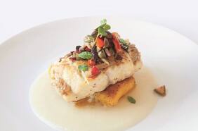 Pescado de roca con polenta sellada sobre emulsión de ajo y limón con aceitunas y verduras asadas