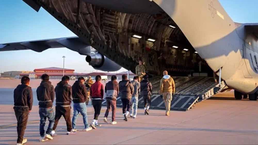 Migrantes esposados abordan un avión militar de Estados Unidos para ser deportados a sus países de origen. Foto: X