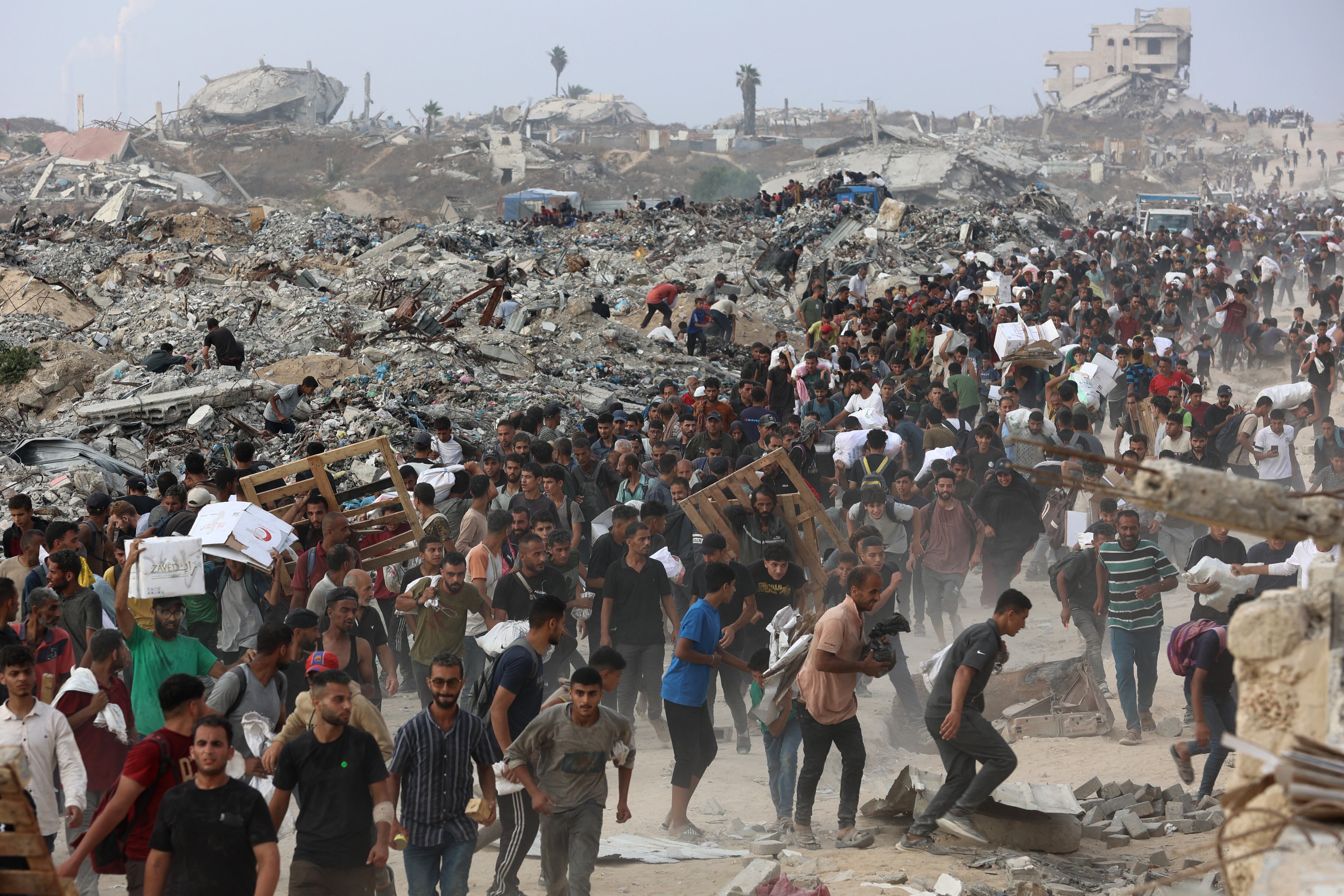 Personas que transportan ayuda caminan por la calle al-Rashid en el oeste de Jabalia, el 22 de junio de 2025, después de que camiones con ayuda humanitaria entraran al norte de la Franja de Gaza a través del cruce fronterizo de Zikim. Foto: Archivo