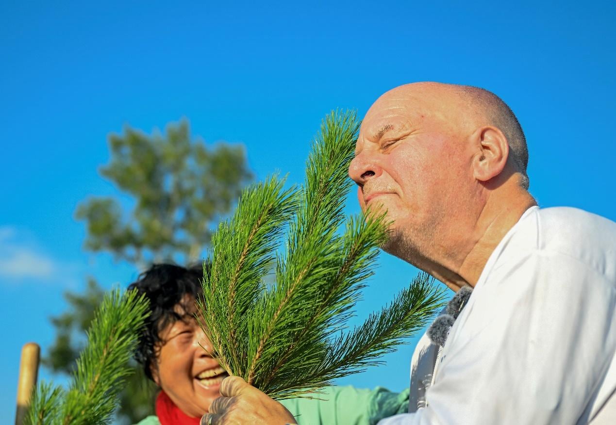 Ronald Sakolsky (d) olfatea un árbol joven que planto con Yin Yuzhen en el área arenosa de Maowusu, en la región autónoma de Mongolia Interior, en el norte de China, el 24 de agosto de 2026. (Xinhua/Lian Zhen)