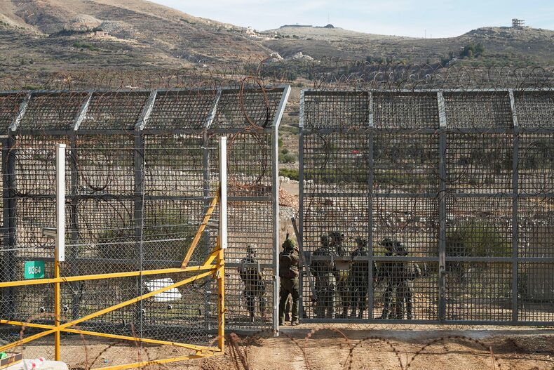 Israeli soldiers syand on the Syrian side of the ceasefire line between Syria and the Israeli-occupied Golan Heights, as seen from the Golan Heights