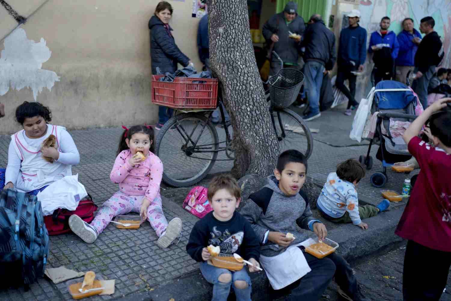 Niños comiendo en la calle tras recibir alimentos de un comedor comunitario en Argentina. Foto: Archivo