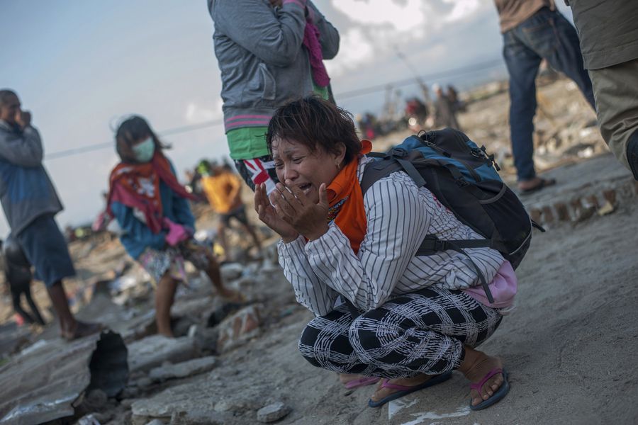 Residents react as rescuers recover the body of a tsunami victim in a